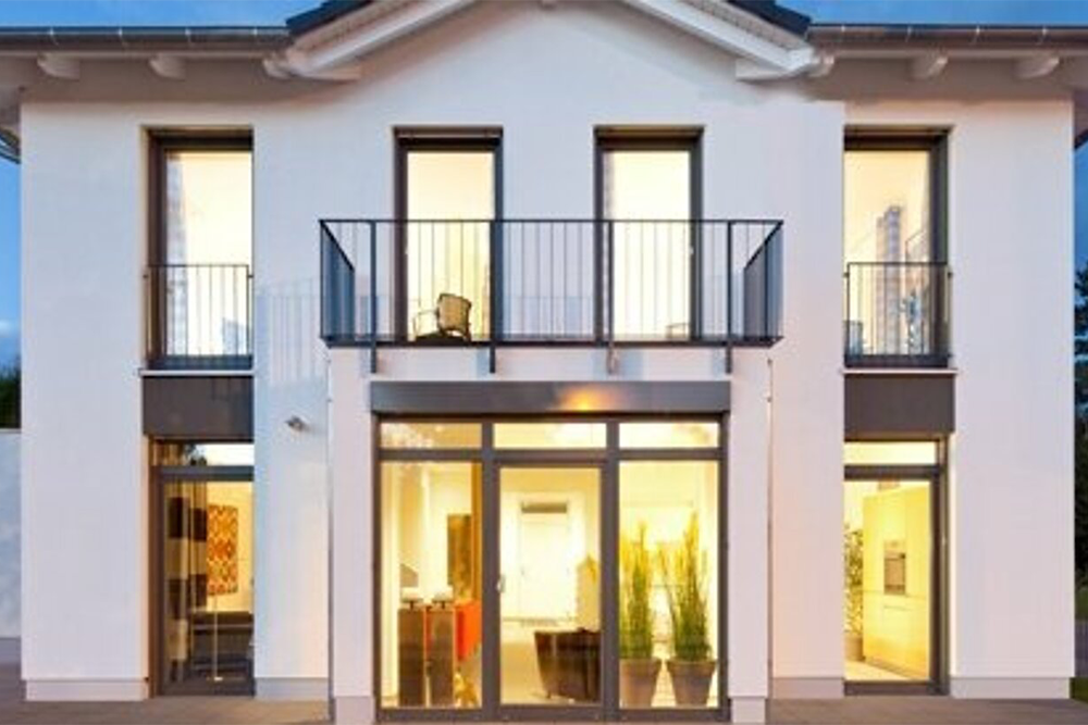 Frontansicht modernes Haus mit großen erleuchteten Fensterfronten